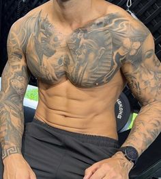 a man with tattoos on his chest sitting down