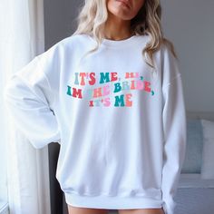 a woman wearing a white sweatshirt that says it's me, i'm the bride it's me