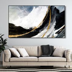 an abstract painting hangs above a couch in a living room with black, white and gold accents