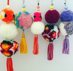 four different colored pom poms hanging from hooks