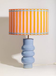 a table lamp with a blue base and orange striped lampshade on the top