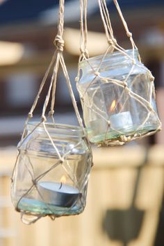 two glass jars with candles hanging from strings