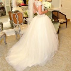 a woman in a wedding dress looking at herself in the mirror with her veil pulled back