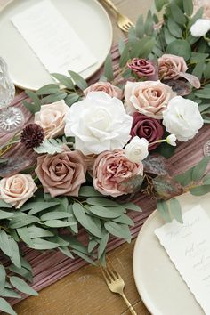 the table is set with pink and white flowers, greenery, and silverware