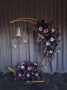 an artistic display with flowers and plants in the shape of a crescent, hanging from a gold frame