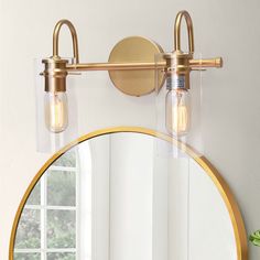 a bathroom mirror with two lights on it and a light fixture above the mirror that is gold