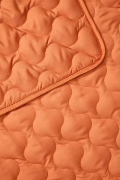 an orange quilted material with circles and lines on the edges, as well as a blanket