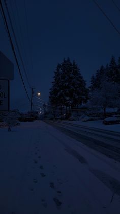 a snowy street at night with snow on the ground and power lines in the background