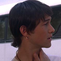 a close up of a person wearing a necklace and earring with a bus in the background