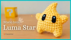 a crocheted yellow star sitting on top of a wooden table next to a question mark