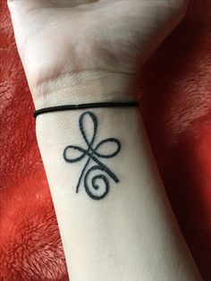 a woman's wrist with a tattoo on it that has an infinite knot in the middle