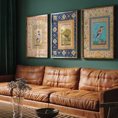 a living room with leather couches and paintings on the wall