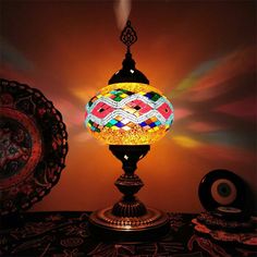 a colorful lamp sitting on top of a wooden table next to a plate and bowl