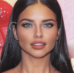 a woman with long black hair and blue eyes is looking at the camera while wearing an earring