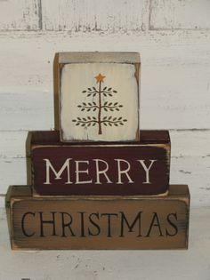 a merry christmas sign with a tree on it's top and two blocks stacked up