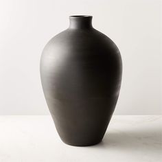 a black vase sitting on top of a white table