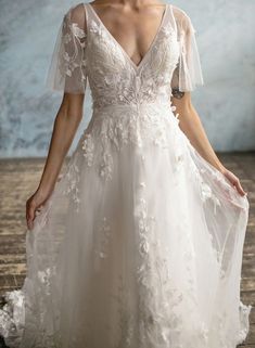 a woman in a white wedding dress standing on a wooden floor