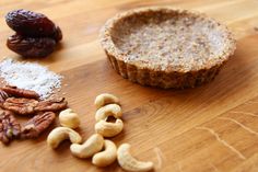 some nuts and other food on a wooden table next to a pie crust, raisins, and pecans