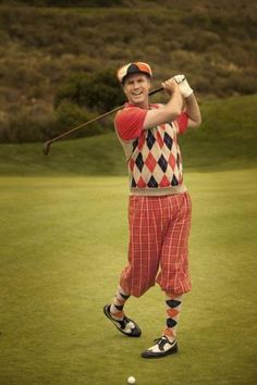 a man in red and white checkered shorts is playing golf on the green grass