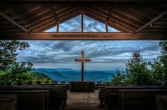 the inside of a church with mountains in the background and a cross at the top