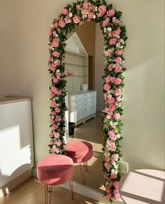 a mirror with pink flowers on it and two stools in front of the mirror