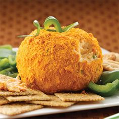 an appetizer ball is on a plate with crackers and green peppers next to it