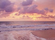 the sun is setting over the ocean with waves crashing on the shore and clouds in the sky