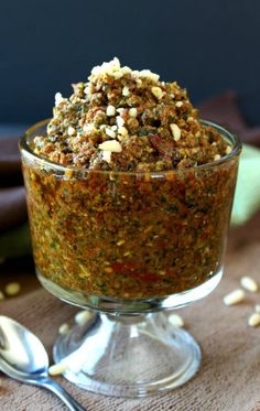 a glass bowl filled with food sitting on top of a table next to a spoon