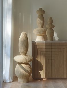 three large vases sitting next to each other on top of a wooden table in front of a window