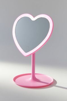 a pink heart shaped mirror sitting on top of a table