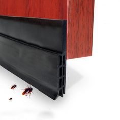 an insect crawling on the floor next to a red wooden door with black slats