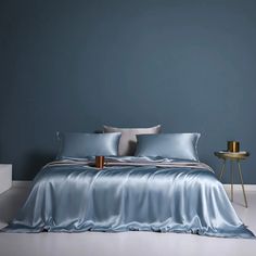 a bed with blue sheets and pillows on top of it in a room that is painted dark blue