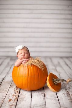 a newborn baby is curled up in a pumpkin with hay on its back and it's eyes closed