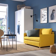 a living room with blue walls and yellow furniture in the corner, along with pictures on the wall