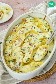 a casserole dish filled with ravioli, peas and cheese on a wooden table