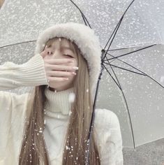 a woman covering her eyes while standing under an umbrella in the rain with snow falling all over her