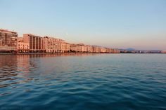 the water is calm and blue with buildings in the background