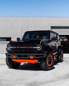 an orange and black truck parked in front of a building