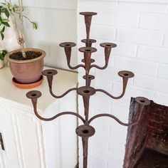 an iron candelabra with six candles on it in front of a potted plant