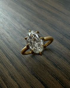 an oval cut diamond sits on top of a wooden table