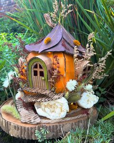 there is a small house made out of wood and flowers on the tree stumps