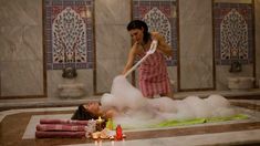 a woman is cleaning the floor with foam from a bathtub while another woman looks on