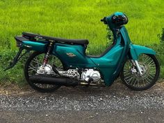 a blue motorcycle parked on the side of a road in front of some green grass