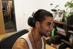 a man wearing headphones sitting in front of a computer desk with books on it