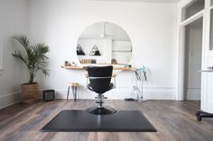 a salon chair sitting on top of a hard wood floor next to a mirror and potted plant