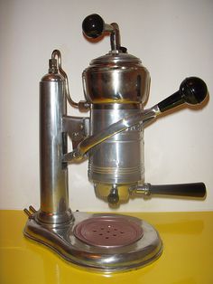 a silver coffee maker sitting on top of a yellow counter