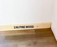 there is a sign that says 1x6 pine wood on the floor in front of a white wall