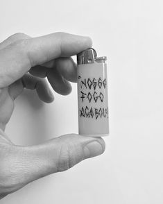 a hand holding a lighter with writing on the front and back of it, in black and white