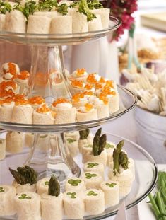 three tiered trays filled with food on top of a table next to flowers