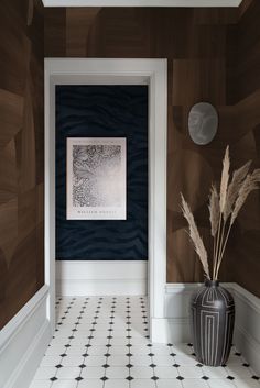 a black and white vase sitting on top of a tiled floor next to a wall